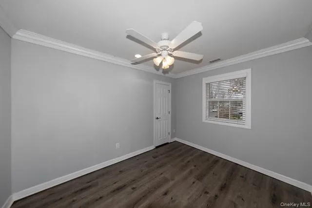 a view of an empty room with wooden floor and a ceiling fan