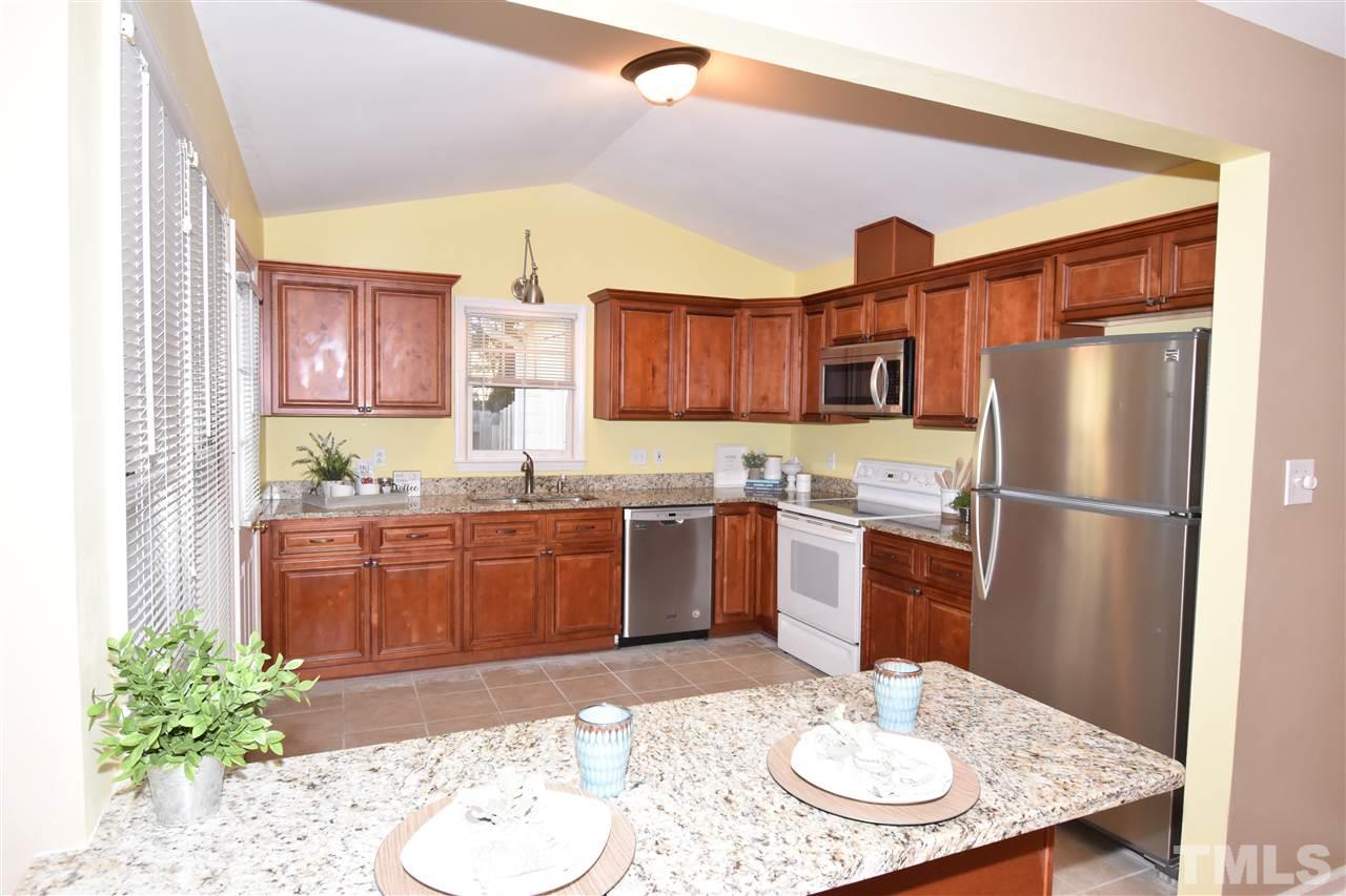 6710 Twin Tree Court Raleigh, NC 27613 - Photo 2 of 18 a kitchen with stainless steel appliances granite countertop a refrigerator a sink dishwasher a stove with wooden cabinets and floor