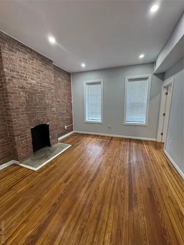 a view of empty room with wooden floor and fireplace