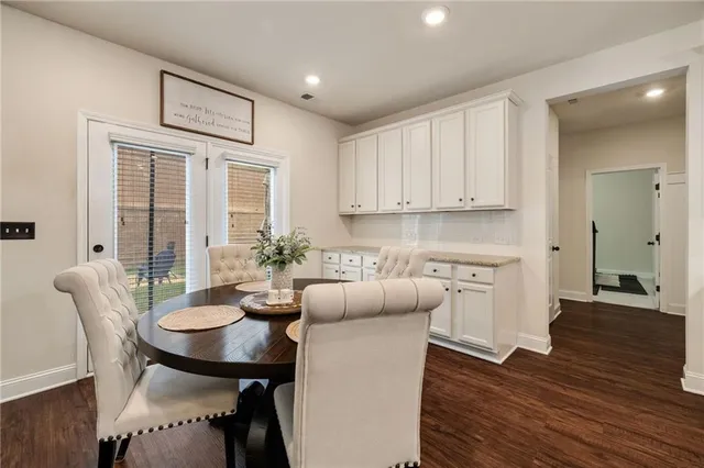 a kitchen with stainless steel appliances granite countertop a dining table chairs and a refrigerator a sink with wooden floor