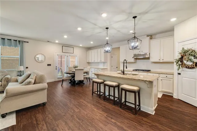 a large kitchen with cabinets a sink a window and chairs