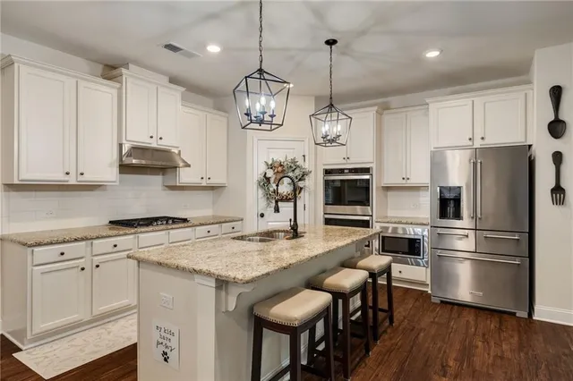 a kitchen with stainless steel appliances granite countertop a stove refrigerator and a wooden floor