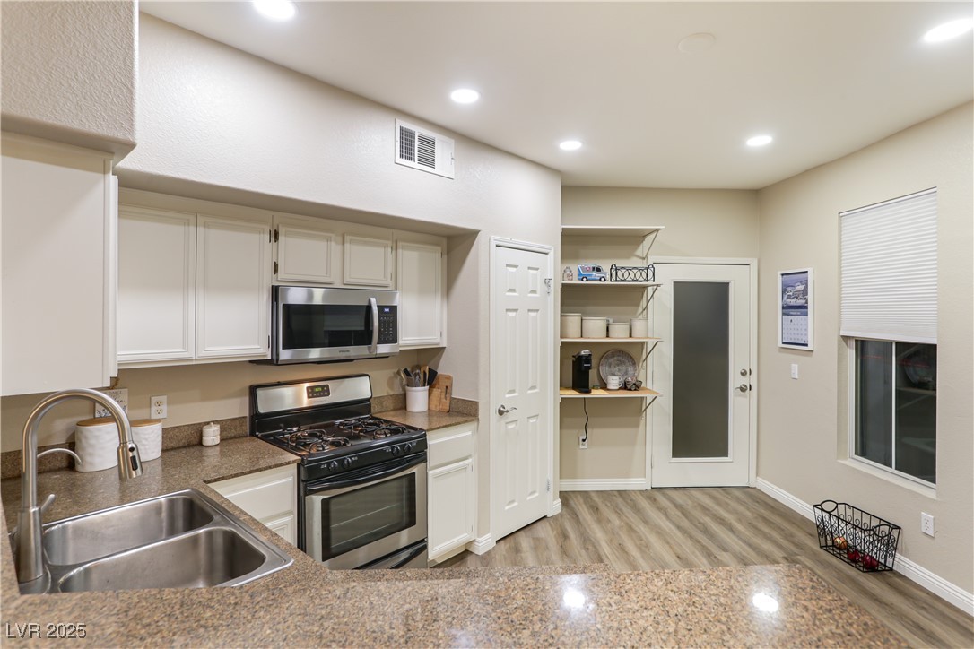 10550 West Alexander Road, Unit 1068 Las Vegas, NV 89129 - Photo 9 of 28 Kitchen featuring stainless steel appliances, recessed lighting, light wood finished floors, and white cabinets