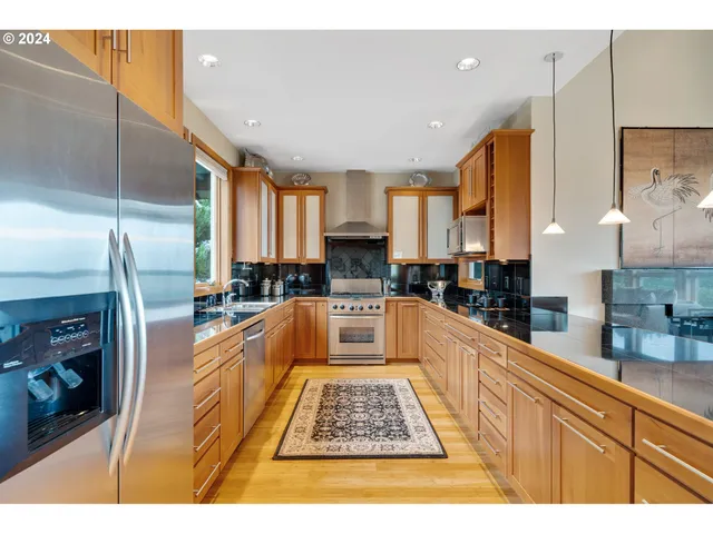 a kitchen with stainless steel appliances granite countertop a stove a sink dishwasher and a refrigerator with wooden floor