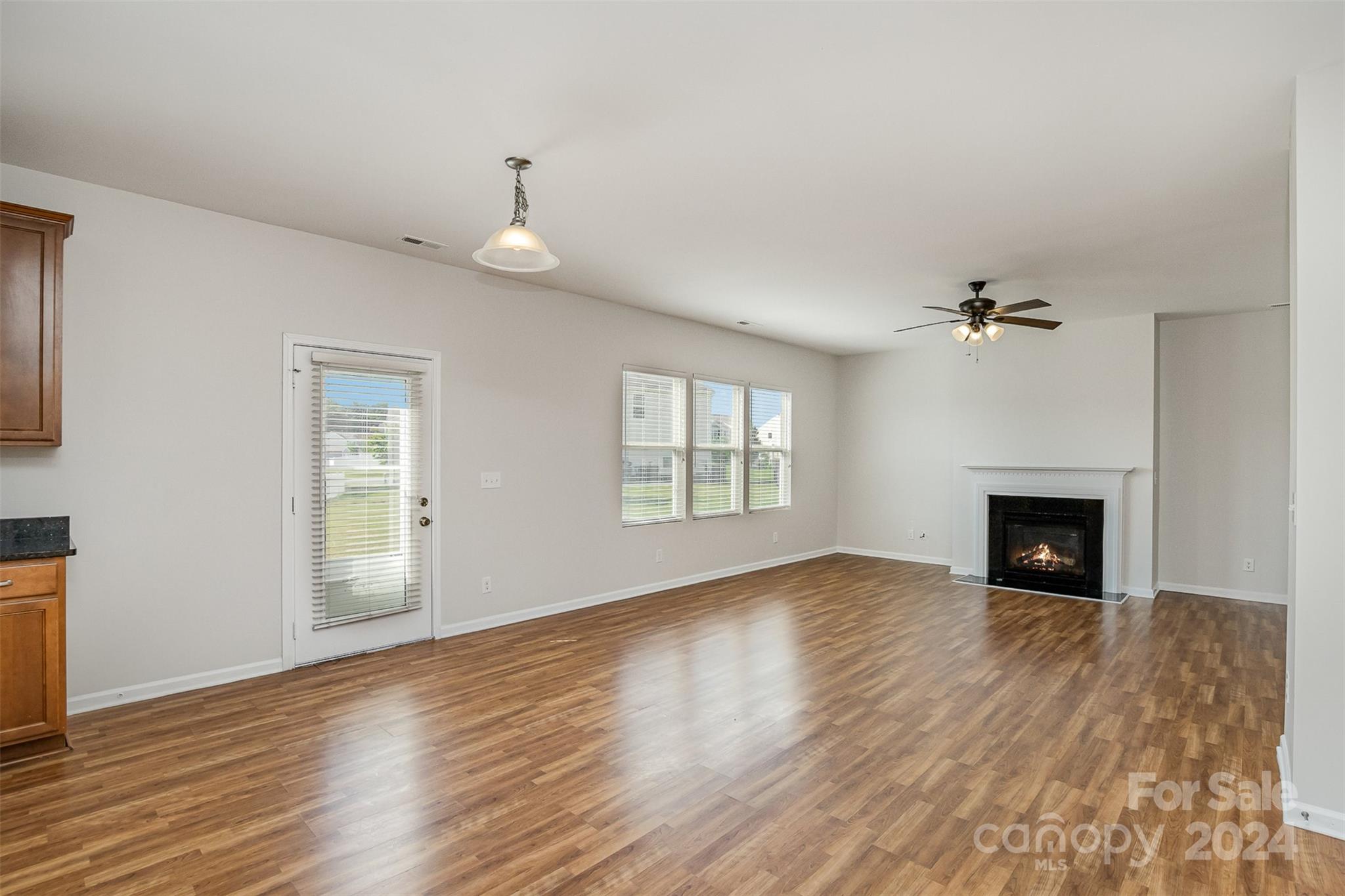7006 Farm Pond Road Indian Trail, NC 28079 - Photo 9 of 37 an empty room with wooden floor fireplace and windows