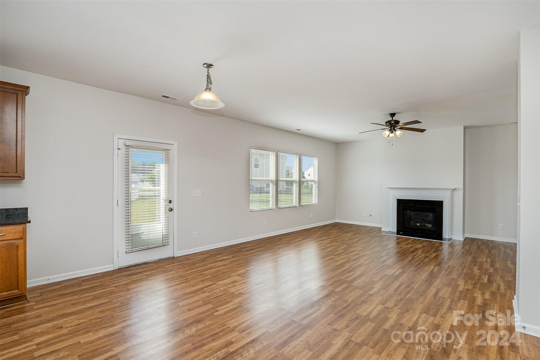 7006 Farm Pond Road Indian Trail, NC 28079 - Photo 10 of 37 an empty room with windows fireplace and wooden floor