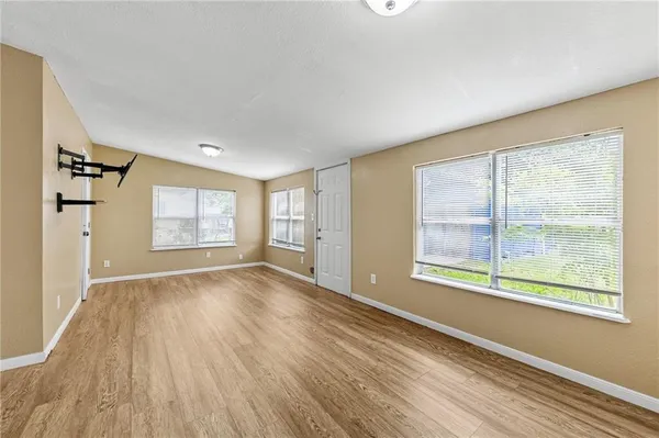 a view of an empty room with a window and wooden floor