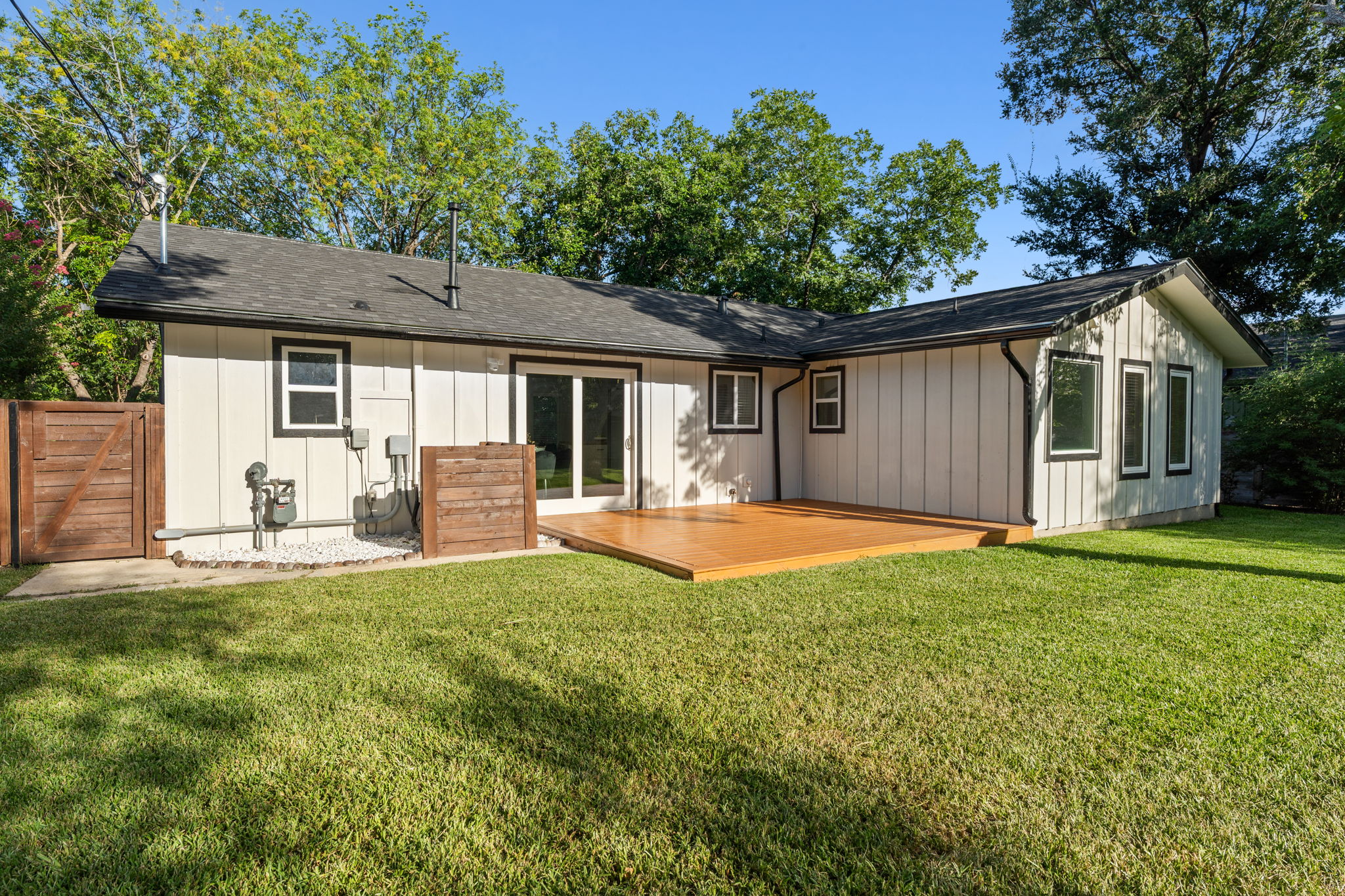 4802 Brighton Road Austin, TX 78745 - Photo 26 of 30 Rear exterior features a spacious deck overlooking the large backyard, creating an ideal setting for outdoor relaxing or entertaining.