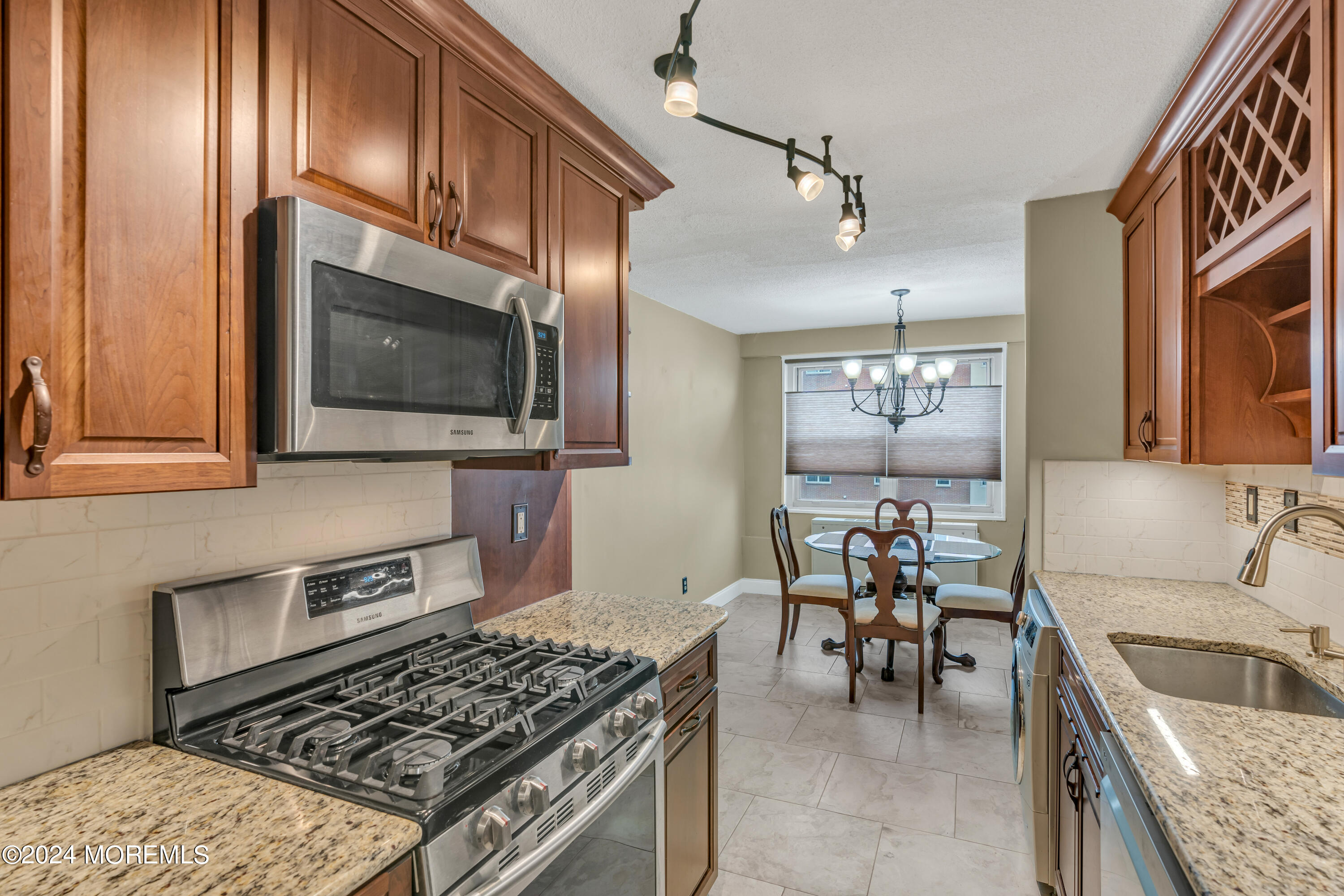 28 Riverside Avenue, Unit 7J Red Bank, NJ 07701 - Photo 12 of 25 a kitchen with stainless steel appliances granite countertop a stove top oven a sink a dining table and chairs with wooden floor