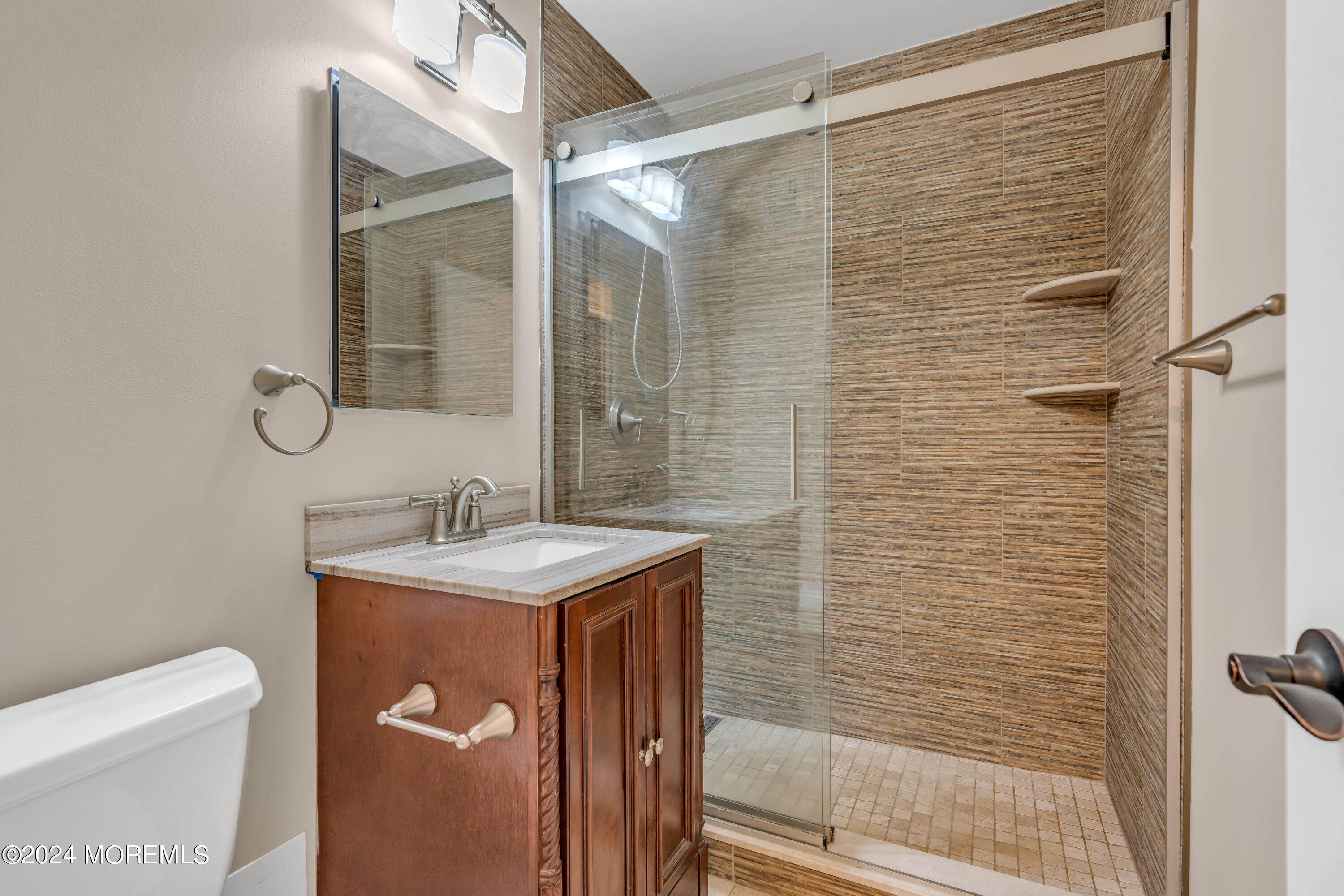28 Riverside Avenue, Unit 7J Red Bank, NJ 07701 - Photo 15 of 25 a bathroom with a granite countertop sink a toilet a mirror and shower