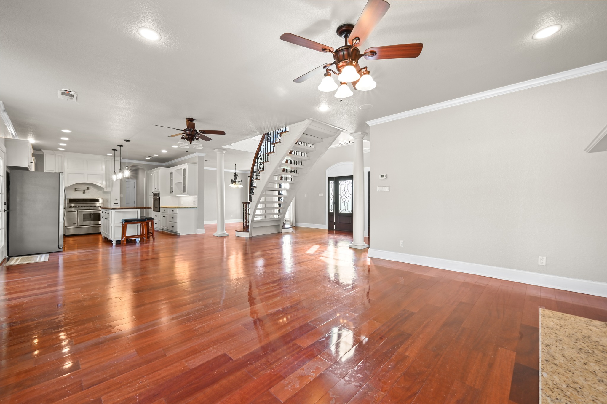 1175 Southern Way Luling, TX 78648 - Photo 19 of 40 Hardwood floors stretch across this open-concept layout, connecting a modern kitchen to an elegant entryway with a sweeping staircase.