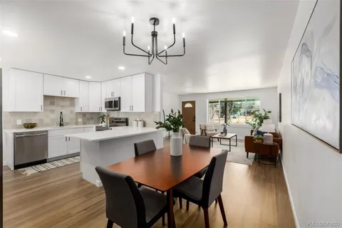 a kitchen with a dining table chairs wooden floor and appliances
