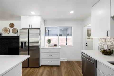 a kitchen with granite countertop a refrigerator a stove and wooden floor