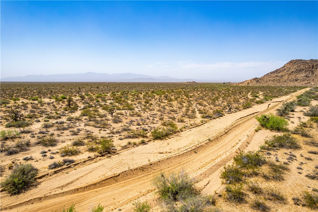 0 East Arroyo Road Yucca, AZ 86438 - Photo 20 of 25 Expansive desert landscape with a dirt road, sparse vegetation, and distant mountains under a clear sky