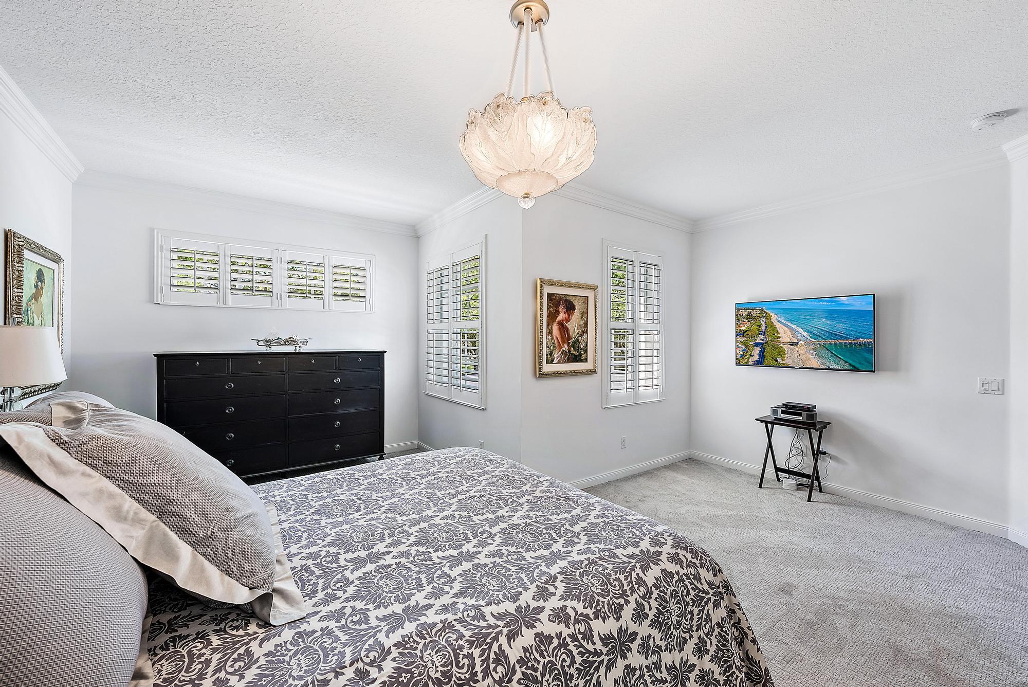 312 Bougainvillea Drive Jupiter, FL 33458 - Photo 20 of 44 a bedroom with a bed and a chandelier