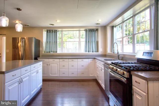 a kitchen with granite countertop a stove a sink wooden floor and glass window
