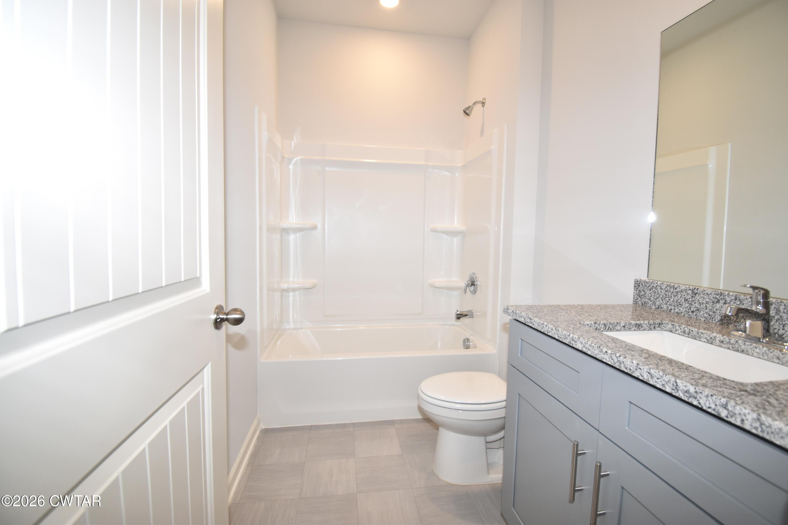 71 Clarendon Cove Jackson, TN 38305 - Photo 15 of 18 a bathroom with a granite countertop sink a toilet a mirror and bathtub