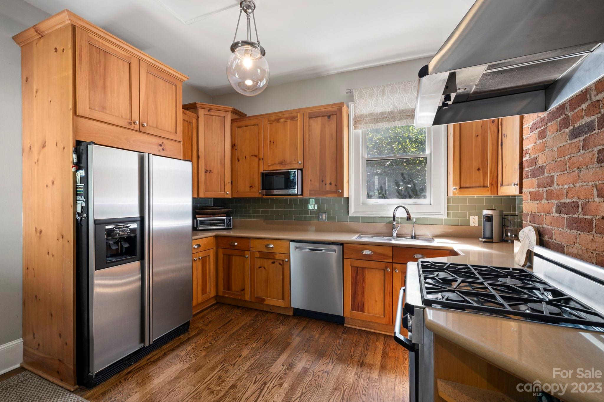 18 Cherokee Road Asheville, NC 28801 - Photo 18 of 45 a kitchen with stainless steel appliances granite countertop a refrigerator a sink dishwasher a stove and white countertops with wooden floor