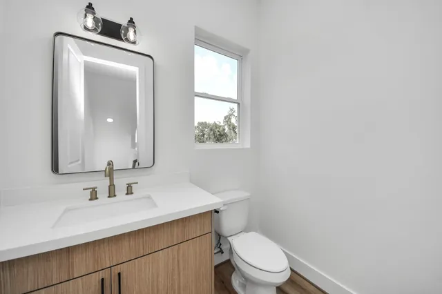 a bathroom with a toilet sink vanity and mirror