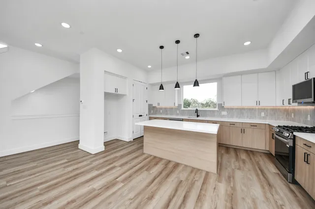 a large kitchen with cabinets wooden floor and stainless steel appliances
