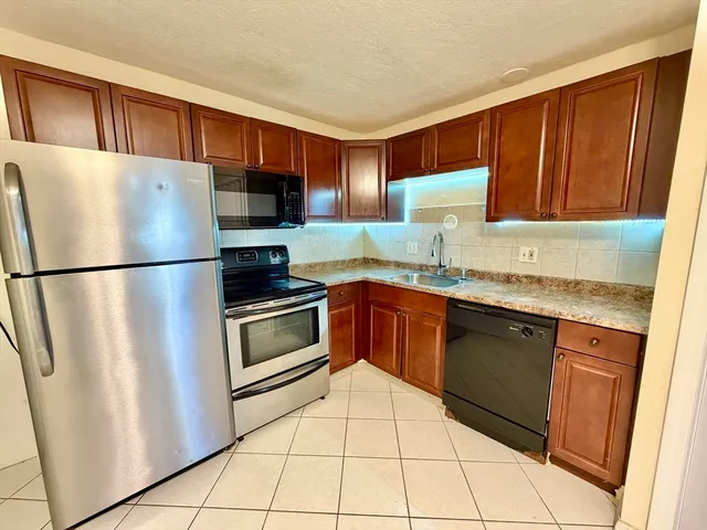 a kitchen with granite countertop a refrigerator and a sink
