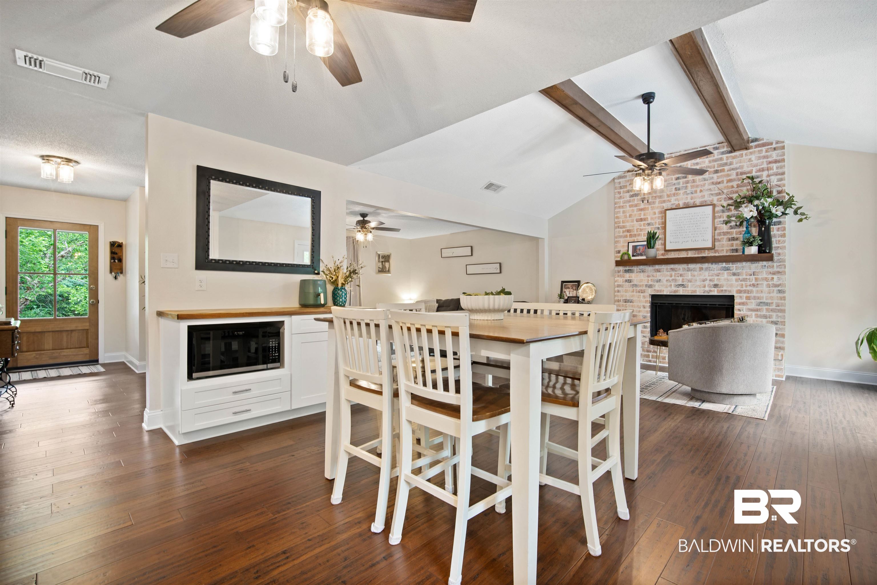 71 Caisson Trace Daphne, AL 36527 - Photo 11 of 36 Vaulted ceiling featuring exposed beams, a brick fireplace with a wood mantle, and wood-finish flooring