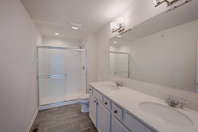 a spacious bathroom with a granite countertop sink a toilet a shower and a mirror
