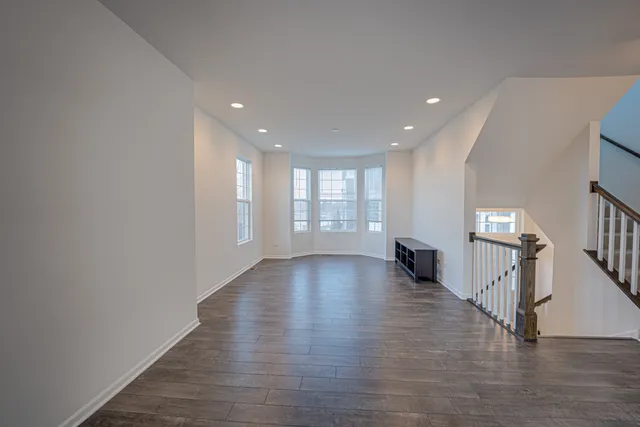 a view of an empty room with wooden floor and stairs