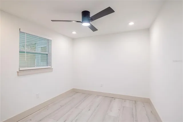 an empty room with a window and a ceiling fan