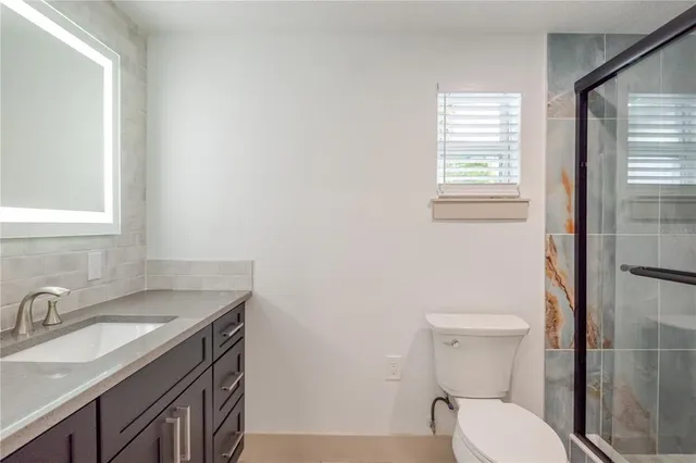 a bathroom with a granite countertop toilet sink and mirror