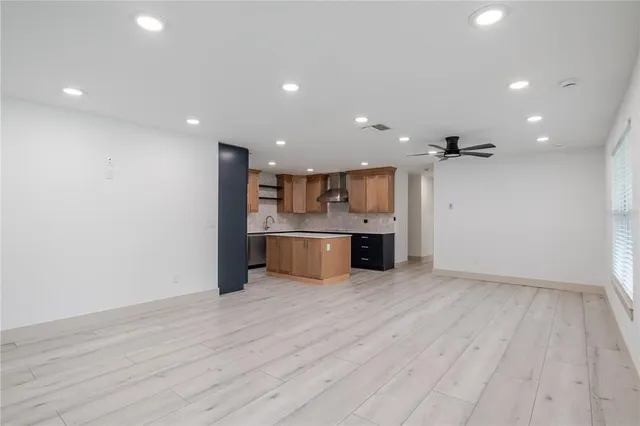 a view of kitchen with kitchen island granite countertop wooden floors and stainless steel appliances