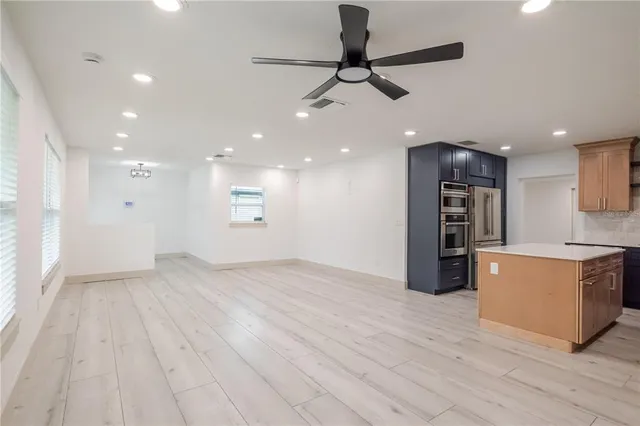 an empty room with wooden floor and a kitchen