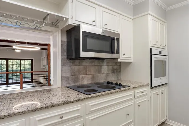a kitchen with stainless steel appliances granite countertop white cabinets and window