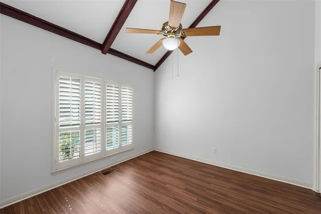 an empty room with wooden floor fan and windows