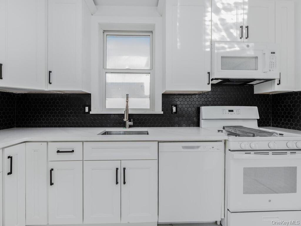 146-84 182nd Street Queens, NY 11413 - Photo 31 of 45 a kitchen with white cabinets and white appliances