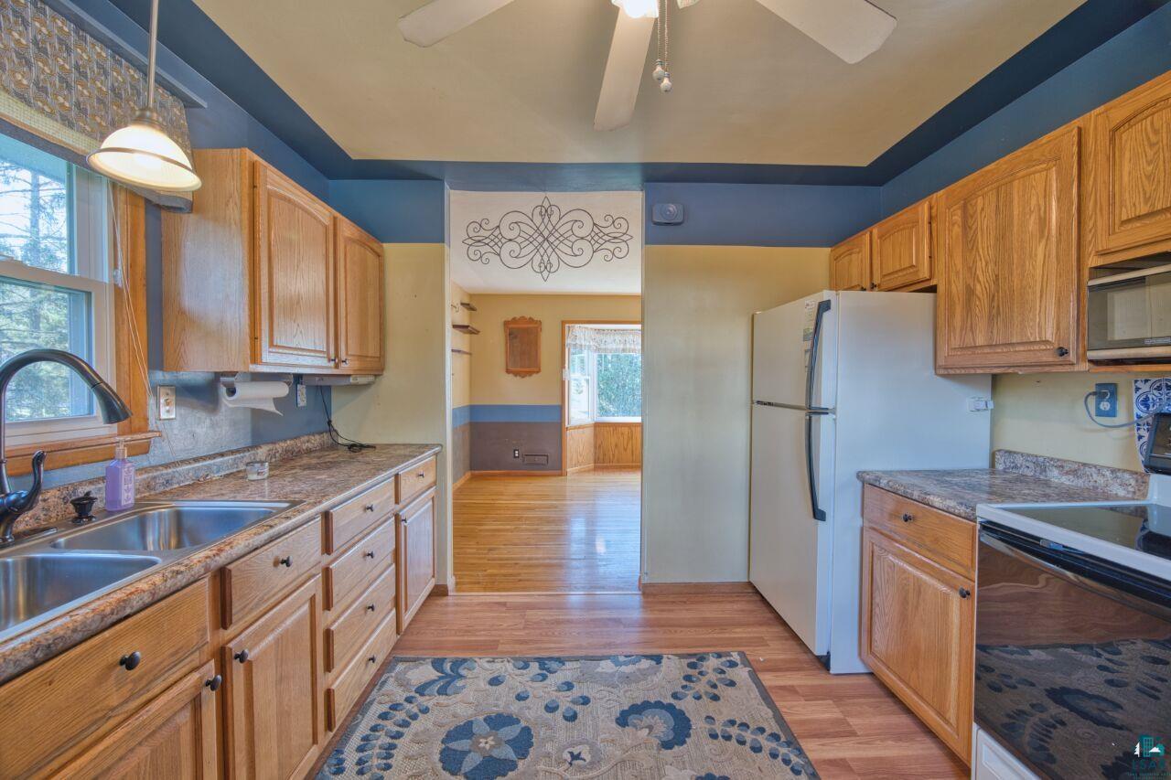 5316 Highway 110 Aurora, MN 55705 - Photo 9 of 35 Kitchen featuring white appliances, light wood-style flooring, a ceiling fan, brown cabinetry, and dark stone countertops