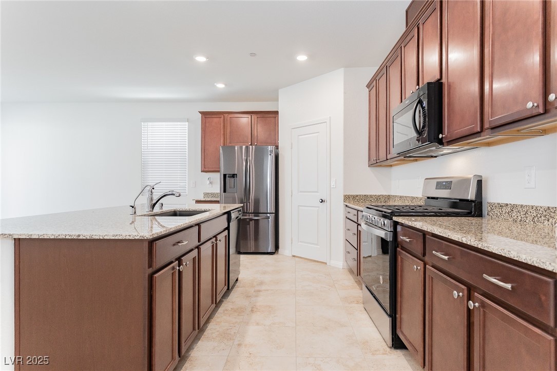 3468 Bradano Lane Henderson, NV 89044 - Photo 13 of 50 Kitchen with stainless steel appliances, light stone countertops, an island with sink, recessed lighting, and light tile patterned flooring