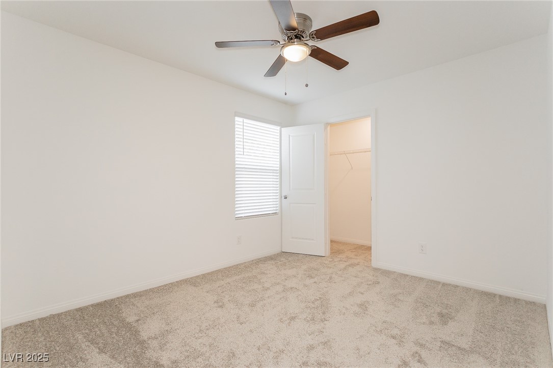 3468 Bradano Lane Henderson, NV 89044 - Photo 30 of 50 Unfurnished bedroom with a walk in closet, light carpet, and a ceiling fan