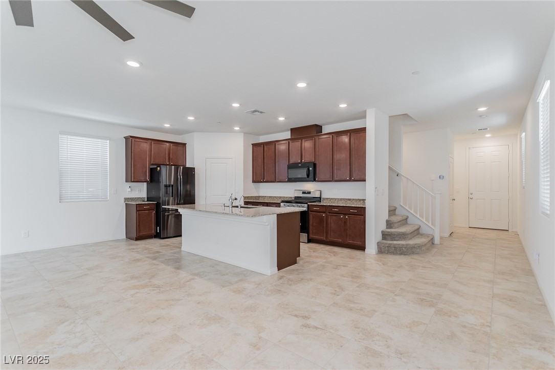 3468 Bradano Lane Henderson, NV 89044 - Photo 9 of 50 Kitchen with stainless steel range, refrigerator with ice dispenser, an island with sink, black microwave, and dark brown cabinetry