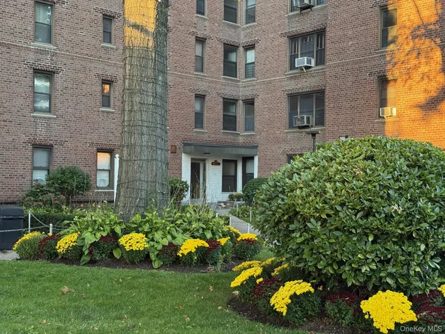 a front view of multi story residential apartment building with yard and outdoor seating