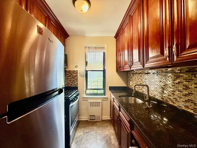 a kitchen with granite countertop a refrigerator a stove and a sink