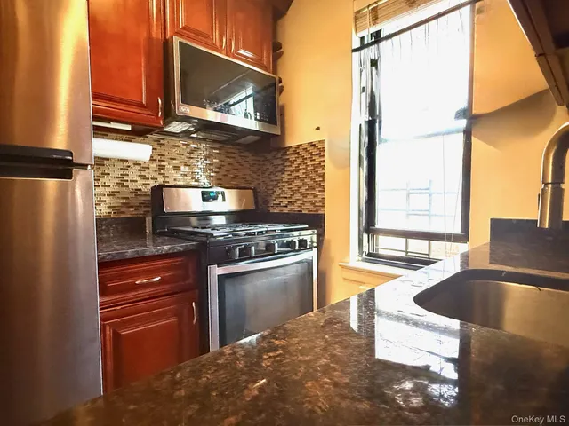 a kitchen with stainless steel appliances granite countertop a stove a sink and a microwave
