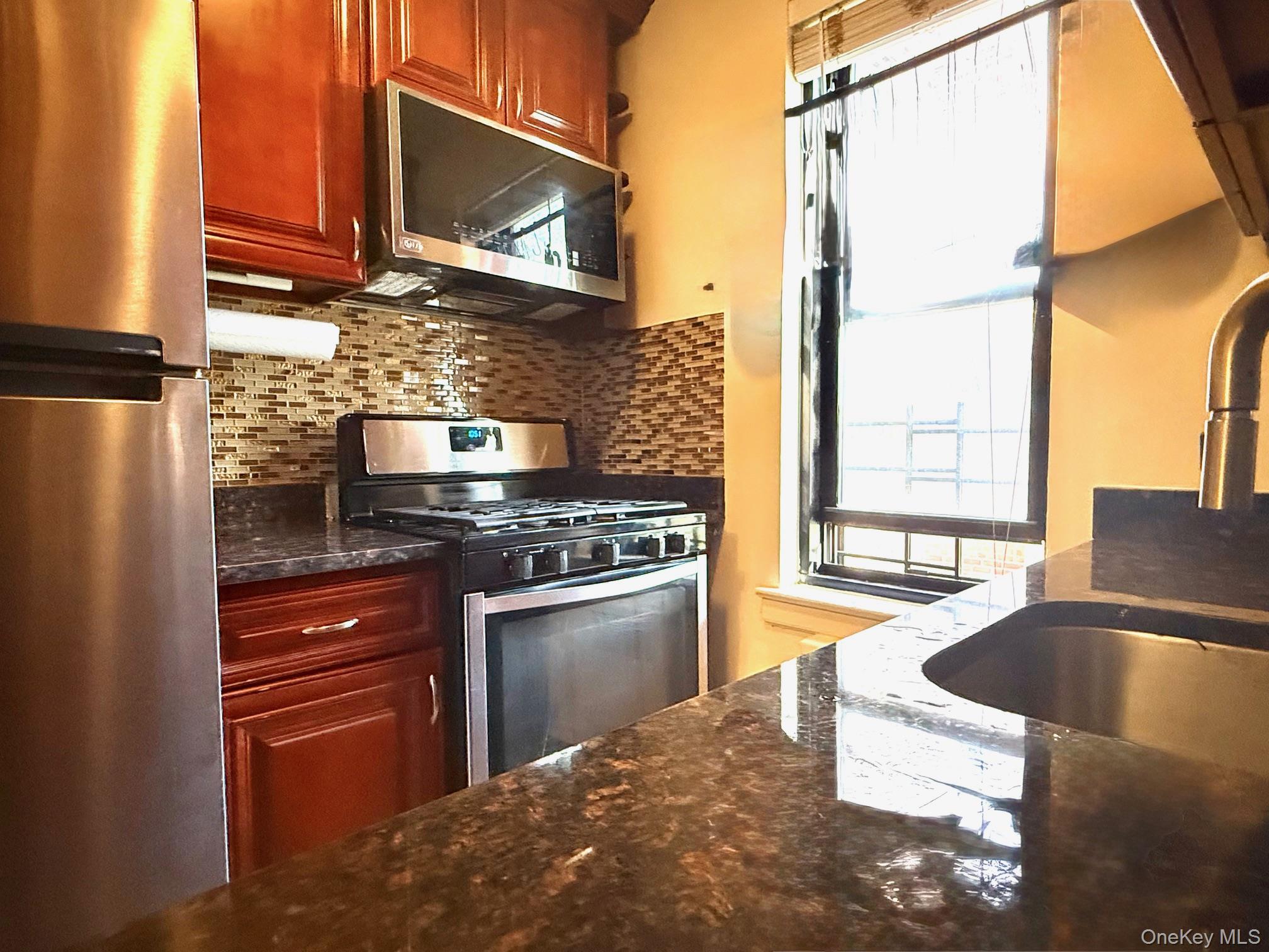 112-25 34th Avenue, Unit 3E Queens, NY 11368 - Photo 10 of 33 a kitchen with stainless steel appliances granite countertop a stove a sink and a microwave