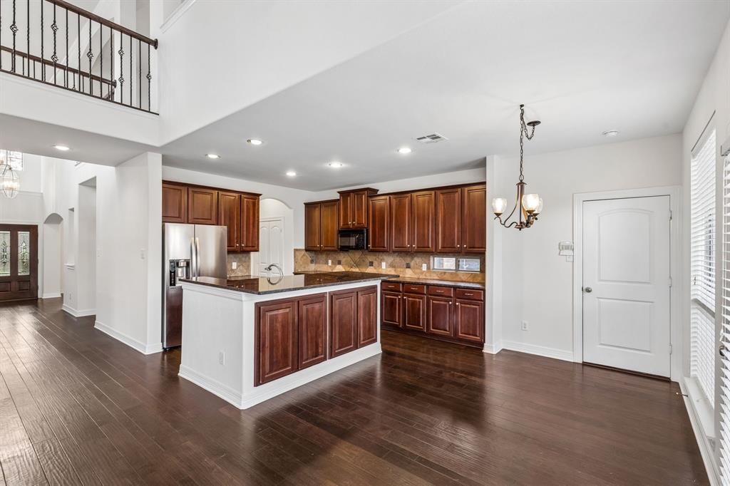 960 Remuda Road Frisco, TX 75033 - Photo 7 of 39 Spacious interior featuring dark wood-finish flooring, a kitchen island with dark cabinetry, stainless steel appliances, and a two-story entry