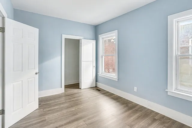 an empty room with wooden floor and windows