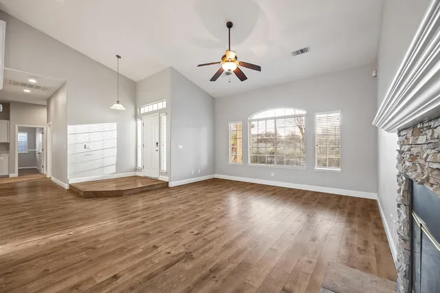 an empty room with wooden floor chandelier and windows