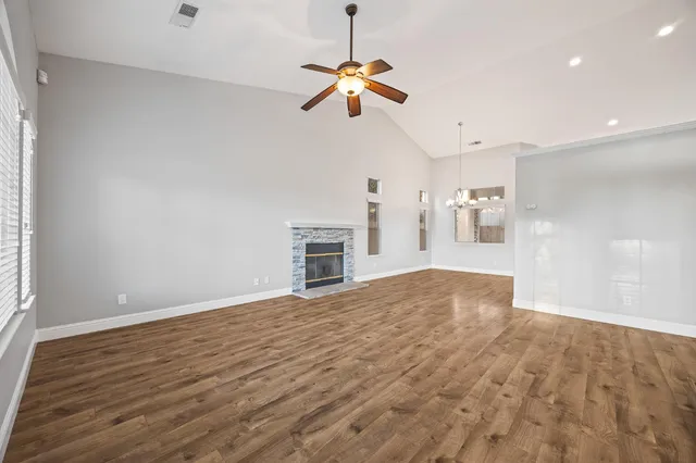 a view of a livingroom with a ceiling fan a kitchen a ceiling fan and windows