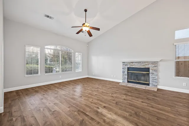 a view of an empty room with wooden floor fireplace and a window