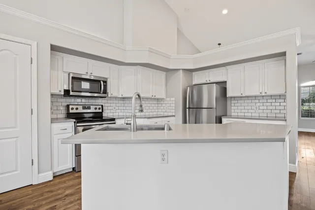 a kitchen with stainless steel appliances granite countertop a refrigerator a stove a sink and a microwave