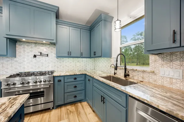 a kitchen with stainless steel appliances granite countertop a sink stove and cabinets